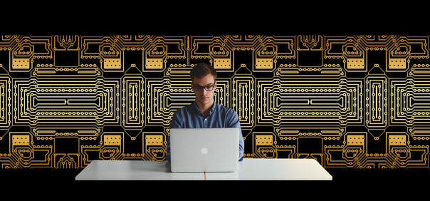 man working on laptop with decorative mural behind him showing the three uses for having a wall mural in your office 